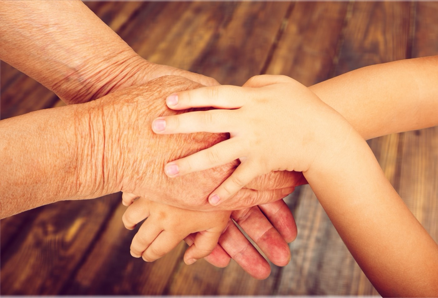 A child's hands resting on an older adult's hand